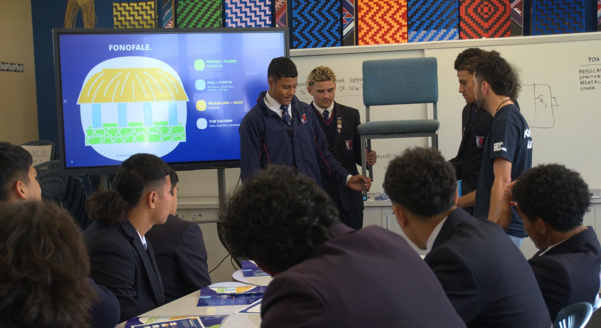 Students gather round table with whiteboard showing the Fonofale wellbeing model